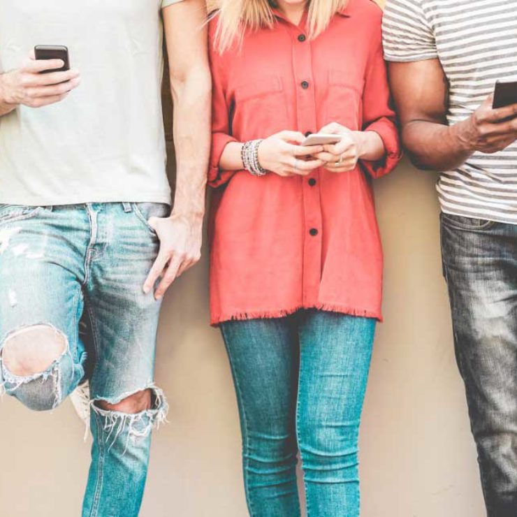 People Standing In A Line Looking At Their Mobile Phones