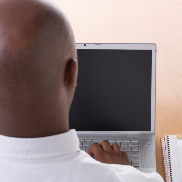 Man sitting in front of computer to demonstrate doing mindfulness exercise while at work