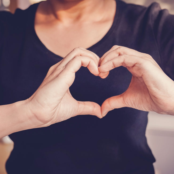 Woman Standing With Her Hands In The Shape Of A Heart