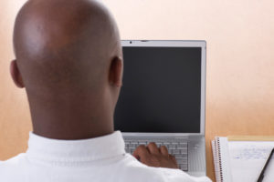 Man sitting in front of computer to demonstrate doing mindfulness exercise while at work