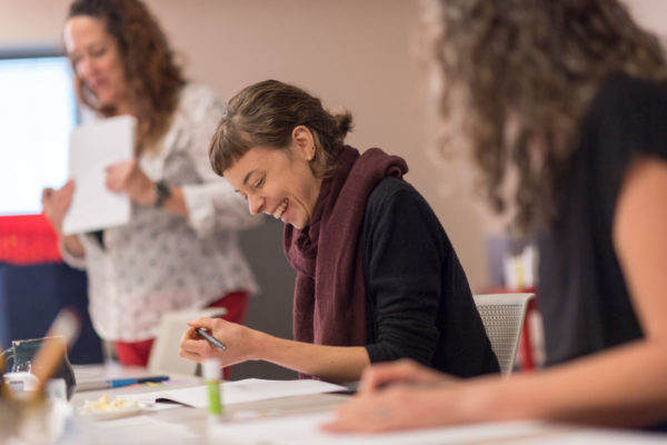 A Drawing Gym Participant Laughs As She Draws In Her Composition Notebook