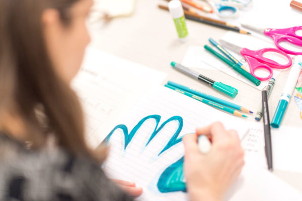 A Drawing Gym Participant Traces Her Hand In Blue Marker In Her Compsition Notebook