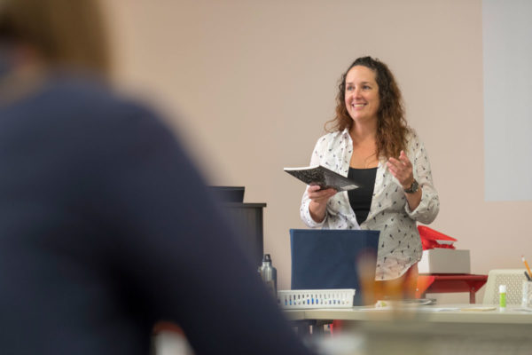 Angela Richardson Holds A Composition Notebook As She Explains How Drawing Gym Participants Will Use It During Sessions