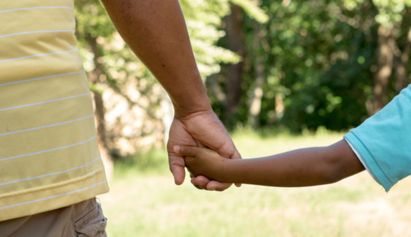 Photo of adult and child holding hands by pixelheadphoto via iStock